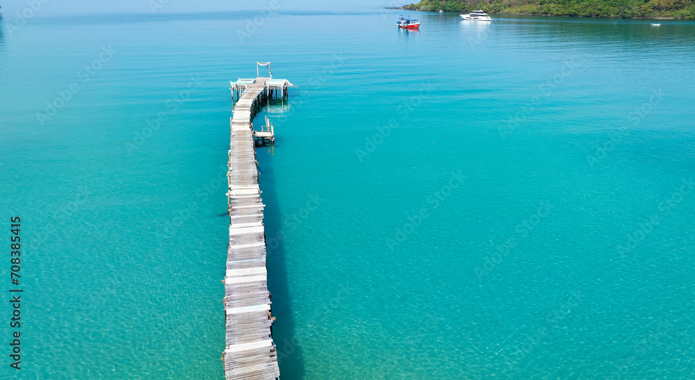 The wooden jetty leads out to the sea with  blue turquoise sea water scene in summer tropical background