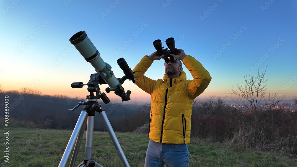 Amateur astronomer observing skies with binoculars and telescope.