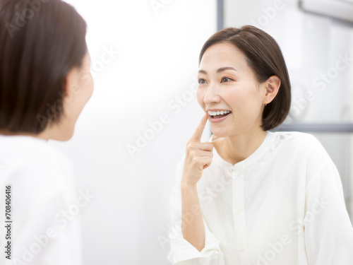 鏡を見ながら歯をチェックするミドル世代女性