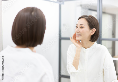 鏡を見ながら肌を触っている40代女性