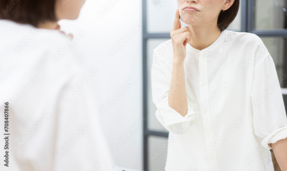 鏡を見ながら指で頬をさわる女性
