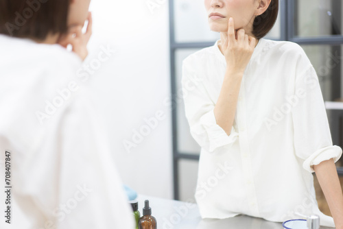 鏡を見ながら肌を見ている40代日本人女性