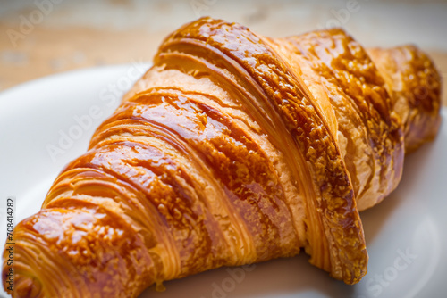 hearty breakfast. a large rosy croissant lies on a white plate  close-up view  delicious food concept