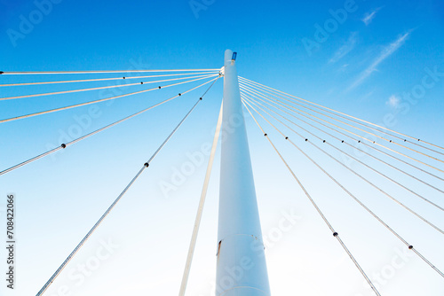 White vertical pillar of a bridge with steel braces, against a background of blue sky, view from below. photo
