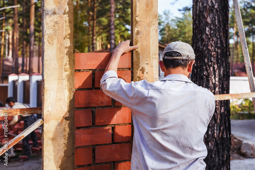 professional construction worker, industrial mason laying bricks, building fence on industrial site