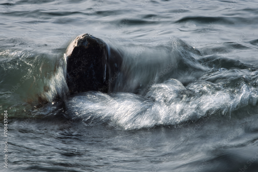 Fototapeta premium Eine dynamische Welle bricht an einem Stein im Bodensee