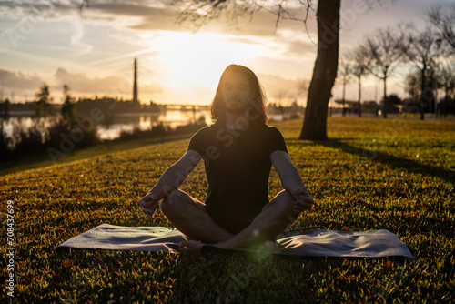 Fototapeta Naklejka Na Ścianę i Meble -  Sunset yoga with the Om Pose. Doing Yoga Outdoors. Meditation