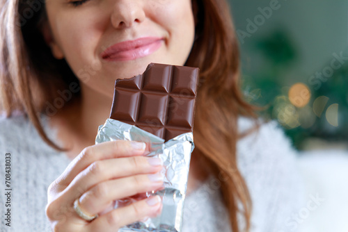 Happy young woman eating chocolate at home