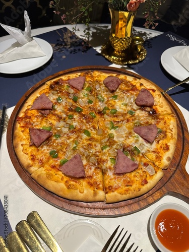 close up of pepperoni salami round pizza in cozy luxurious dining table set up of traditional middle eastern oriental theme table and sofa design