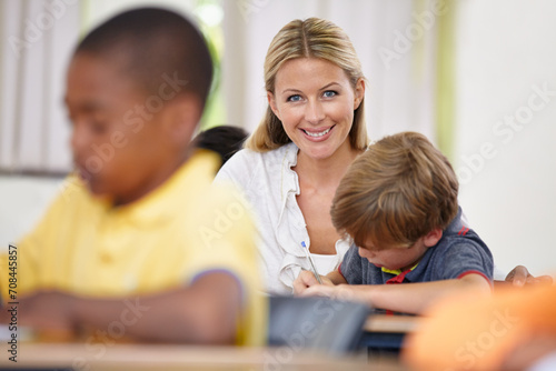 Portrait of teacher, kid or writing in classroom for learning, education and helping for development. Happy woman teaching, boy or child student with knowledge, support or notebook at middle school
