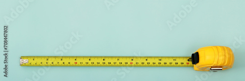 The yellow measuring tape for the mason is placed on a blue background. Soft focus. photo
