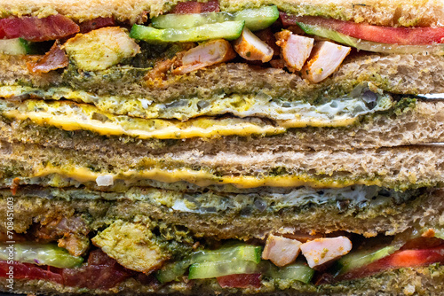 Healthy high protein grilled chicken tikka sandwich wheat bread layered with vegetables and egg closeup