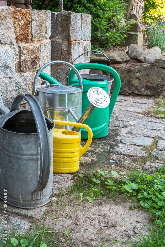 Garden watering can in front of stone well during drought Garden watering can in front of stone well during drought