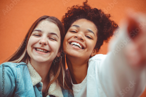 Self-portrait of two happy joyful teen girls of different races making selfie, enjoying friendship. photo