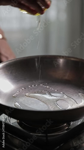 Closeup video of cooking oil being poured in cooker on the gas stove while cooking photo