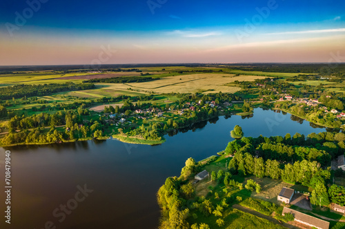Aerial view of Ostrovno lakes, green fields and trees, small villages, summer at sunset, Belarus, Europe