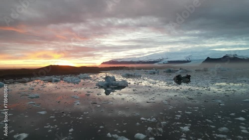 Spectacular drone aerial view of a beautiful sunset reflecting off Iceland's largest glacier, Glacial Lake, and floating giant pieces of glacier, Jokulsarlon and Vatnajökull gracier, Iceland. photo