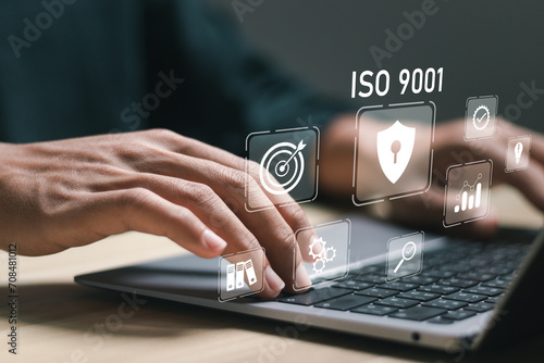 ISO 9001 Standard certification standardisation quality control concept, businessman use laptop with virtual screen of ISO 9001 icons for quality management of organizations.
