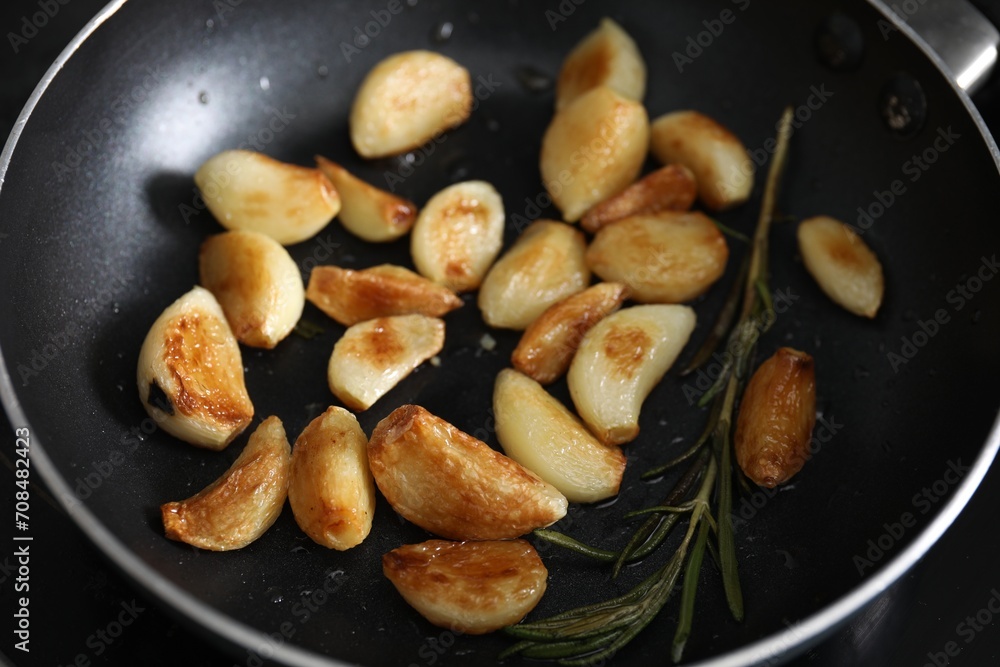 Frying pan with fried garlic cloves and rosemary, closeup Frying pan with fried garlic cloves and rosemary, closeup