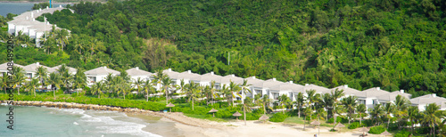 Panorama view white sandy beach with row houses, luxury vacation homes, ocean view villas surrounding by coconut palm trees, mountain, lush green tropical forest background Hon Tre, Nha Trang photo