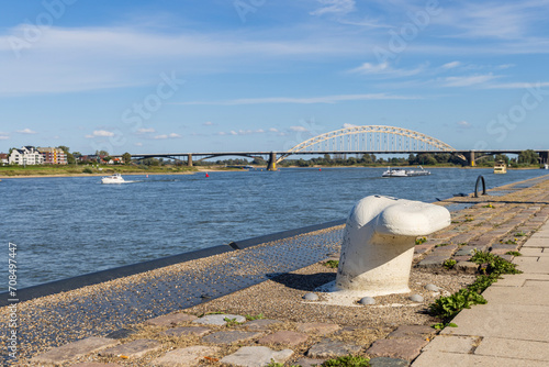 Cityscape of Nijmegen with scenic view on cargo boats passing the bridge in river Waal on a sunny autumn day. photo