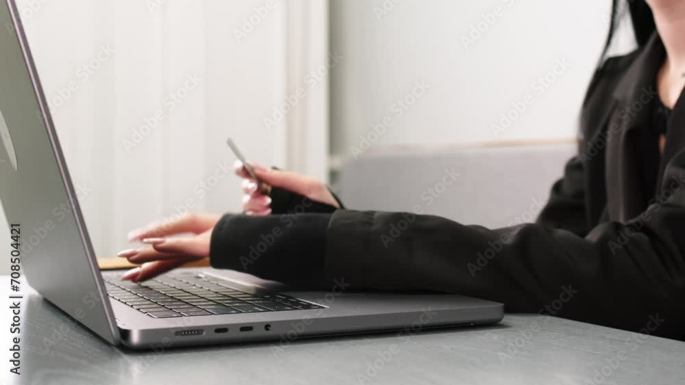 Close-up of a young woman's hands making online purchases through a laptop at a table in a room with a bank card. Online shopping and using credit cards concept. Close-up of a young woman's hands making online purchases through a laptop at a table in a room with a bank card. Online shopping and using credit cards concept.