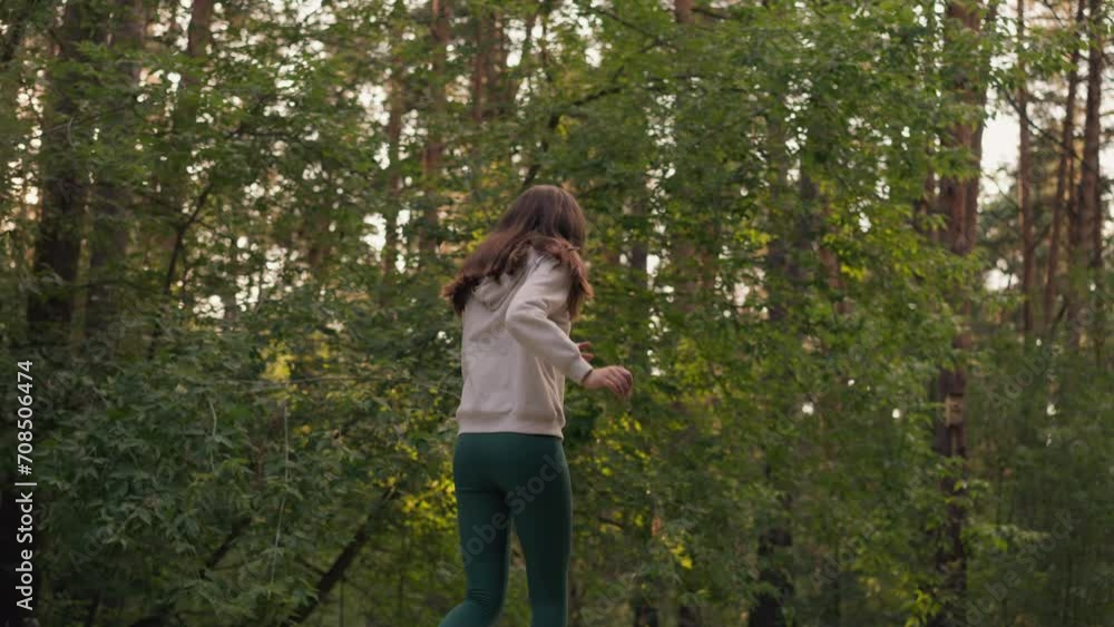 Young lady sprints in forest in evening. Woman runs intensity moving arms for active cardio workout. Female athlete does sports running past trees Young lady sprints in forest in evening. Woman runs intensity moving arms for active cardio workout. Female athlete does sports running past trees