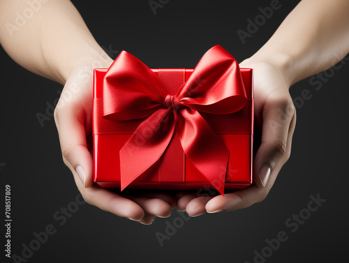 Woman hands holding gift box red wrapping paper, bow and ribbon on white background. Present on Valentine's day, Women's day, Birthday, wadding, Christmas surprise