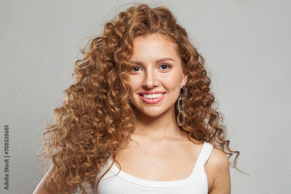 Joyful young female model healthy woman with long wavy frizzy hairstyle and clear skin studio portrait. Hair care, facial treatment and cosmetology concept
