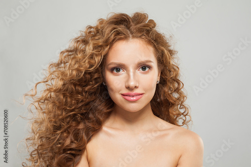 Cute young female model healthy woman with long wavy frizzy hairstyle and clear skin studio portrait. Hair care, facial treatment and cosmetology concept