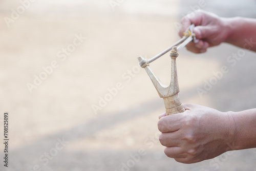 Close up hands hold wooden slingshot for playing shooting game outdoor. Concept ,Thai traditional weapon that use to shoot birds, fish , for fight game or other purposes.      photo