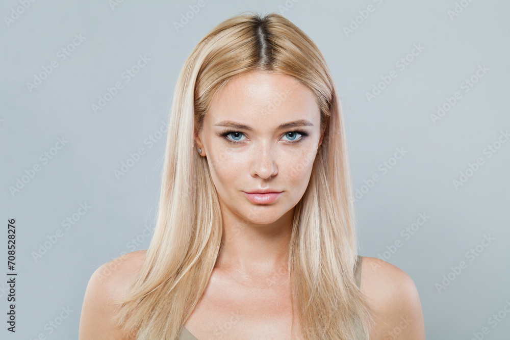 Lovely blonde woman with long straight hair and clean fresh pure perfect skin isolated on gray background, studio portrait Lovely blonde woman with long straight hair and clean fresh pure perfect skin isolated on gray background, studio portrait