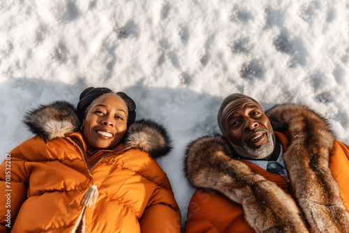 A happy married couple of Africans lay down on the snow-covered ground