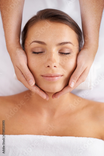 Woman, facial and massage at spa from above for beauty, skincare treatment and healing at cosmetics salon. Face of calm client relax at wellness resort for reiki, break and peaceful holistic therapy