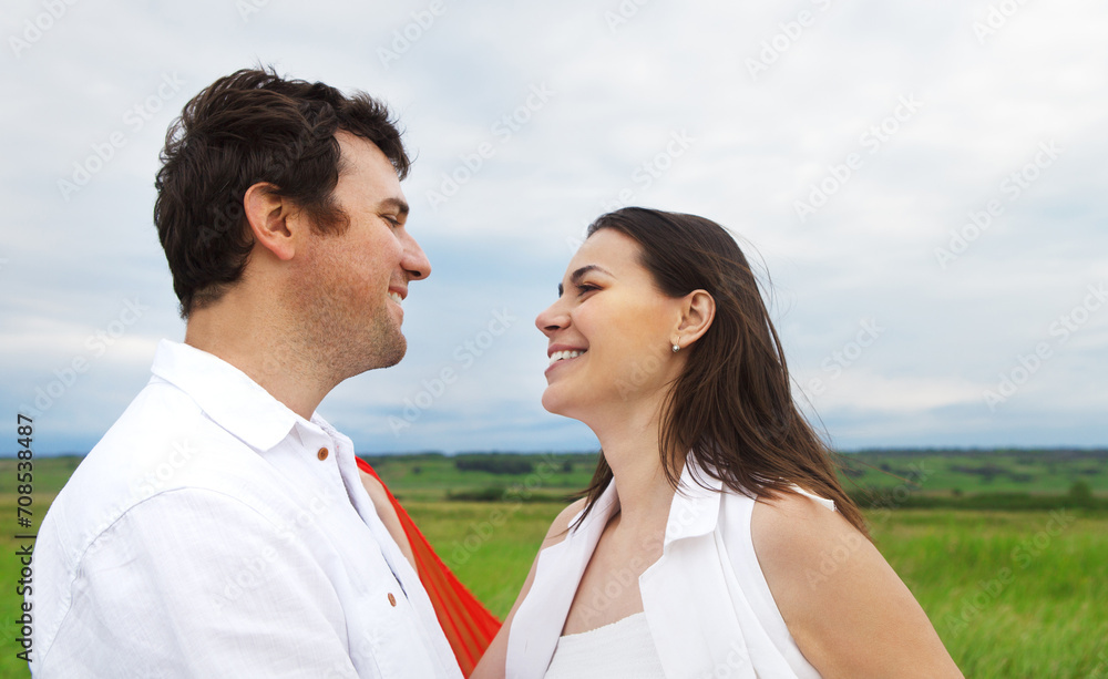 Young happy couple in love with red fabric in summer day Young happy couple in love with red fabric in summer day