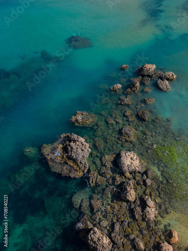 Sharp rocks formation in turquoise sea in Malta aerial top down. Vertical background photo. Natural sea colors palette in Mediterranean paradise.