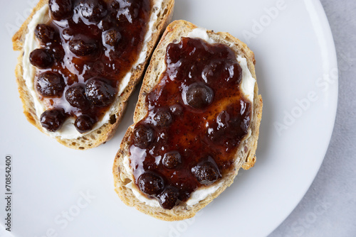 Whole grain bread with strawberry jam on top. Composition with delicious homemade jam on a plate. Breakfast and snack concept.