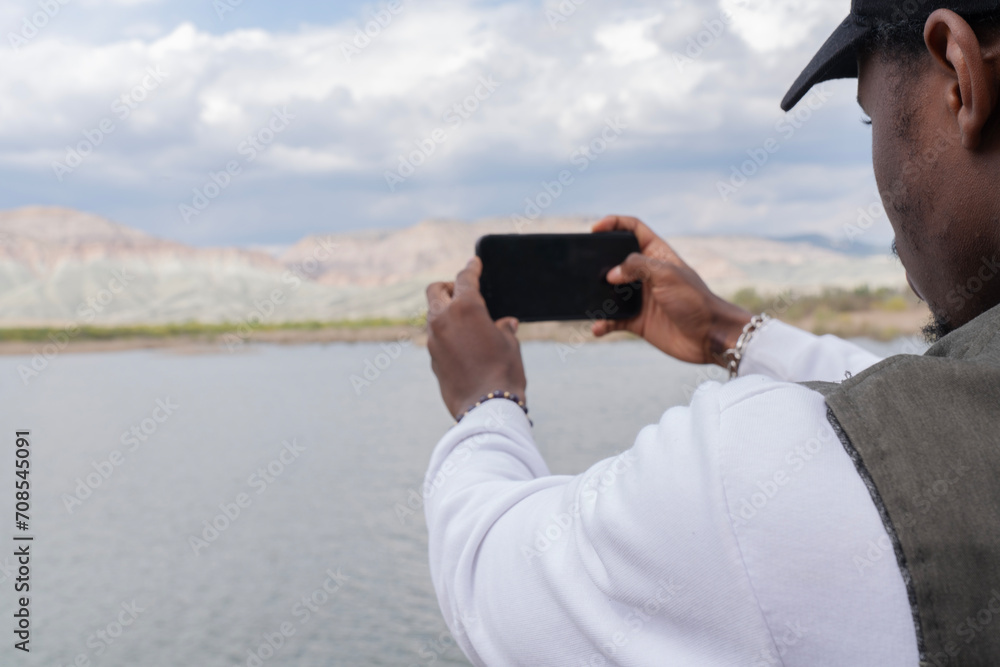 young man takes pictures of lake landscape on her phone