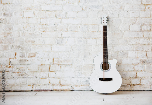 Acoustic white guitar leaning against a white wall in an empty room © Dasha Petrenko