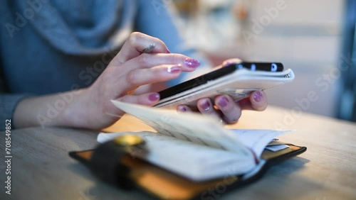 手帳を見ながらスマートフォンを操作する女性の手元 photo