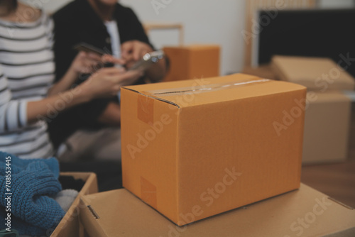 Two Asian blogger showing clothes in front of the camera to recording vlog video live streaming at her shop. Online Shopping Cart notion. on sofa at home