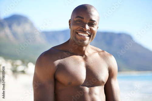 Portrait of black man on beach, holiday and smile with freedom, sunshine and tropical island travel. Sea, mountain and person on ocean vacation in summer with adventure, peace and blurred background.