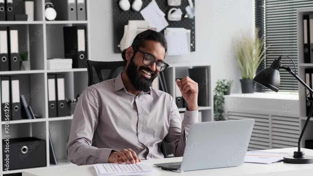 Happy Indian businessman, suited in executive dress, shares laughter and engages in a video call in the office. Contagious laughter and animated expressions reflect the positive connections made. Happy Indian businessman, suited in executive dress, shares laughter and engages in a video call in the office. Contagious laughter and animated expressions reflect the positive connections made.