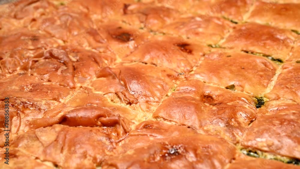 freshly baked spanakopita (spinach pie) in tray rotating freshly baked spanakopita (spinach pie) in tray rotating