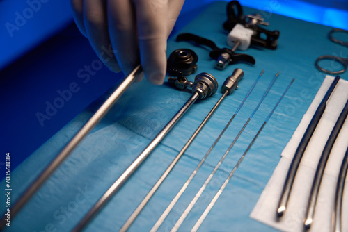 Close up of partial doctor hand taking hysteroscope from table photo