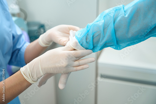 Cropped of nurse helping male doctor put on latex glove on hand before surgery