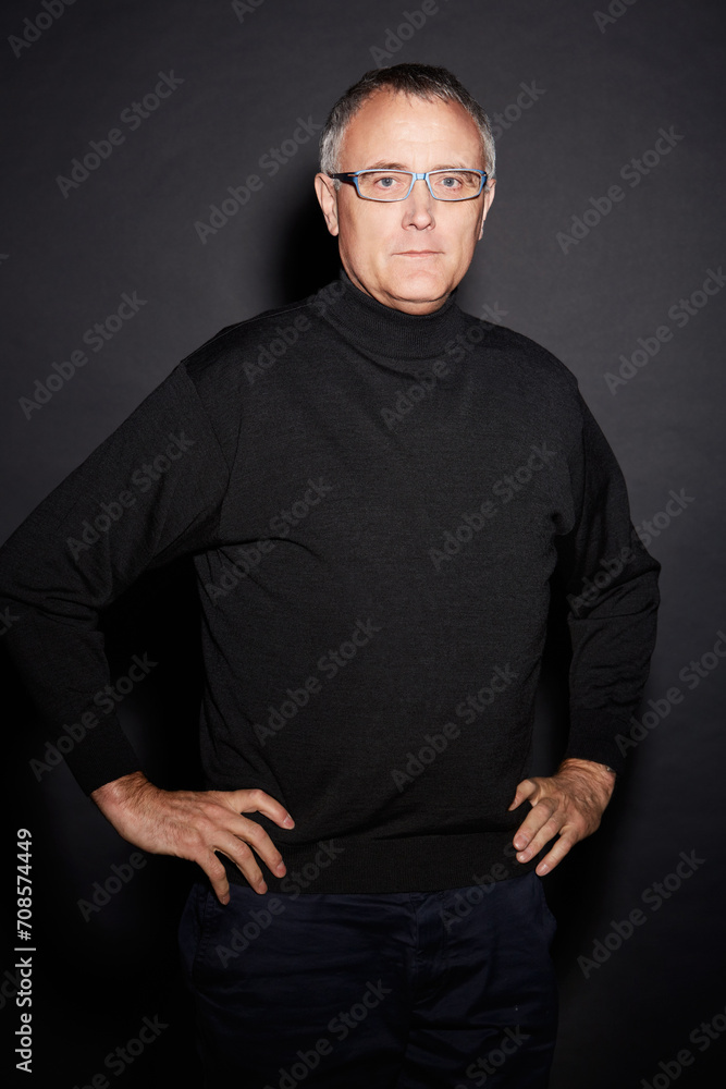 Portrait of mature man in studio with confidence, glasses and dark fashion style in retirement. Pride, relax and senior person isolated on black background with expert knowledge, mystery and wisdom.