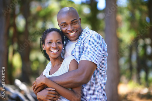 Hug, portrait or black couple hiking in forest to relax or bond on holiday vacation together in nature. Happy, travel or African woman with smile or man in woods trekking on outdoor park adventure