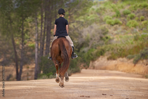 Equestrian, trail and riding a horse in nature on adventure and journey in countryside. Ranch, animal and back of rider outdoor with pet on path in forest or woods for hobby on farm in summer