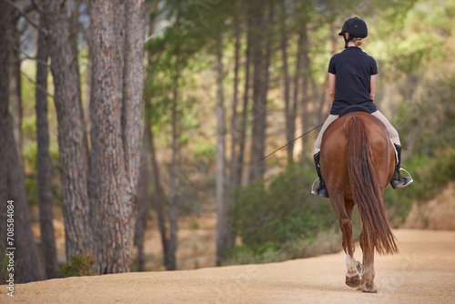 Equestrian, riding and horse on trail in nature on adventure and journey in countryside mockup. Ranch, animal and back of rider outdoor with pet on path in forest or woods for hobby on farm in summer © Tasneem H/peopleimages.com